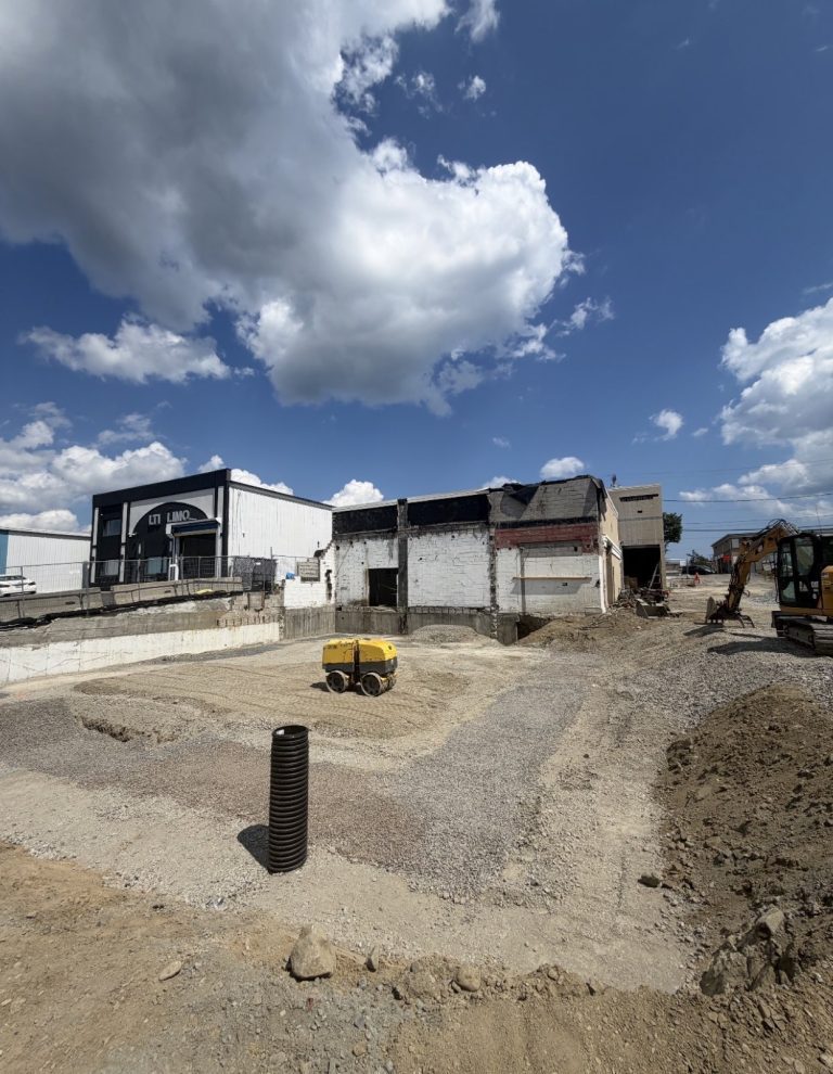 Foundation excavation, drainage risers, and earthmoving equipment at 55 American Legion Highway.