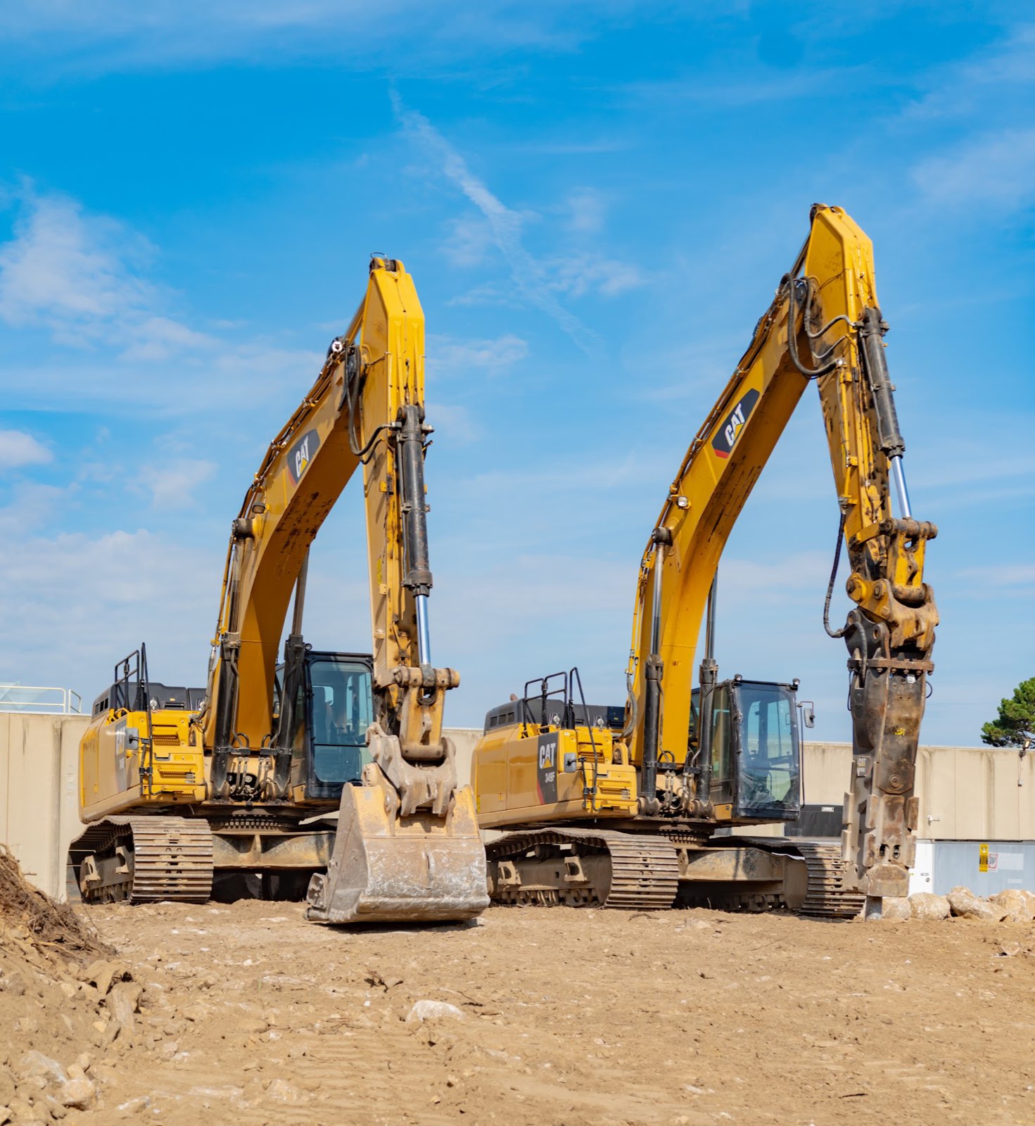 Excavators with bucket and hydraulic breaker attachments beside the existing Applied Materials building.