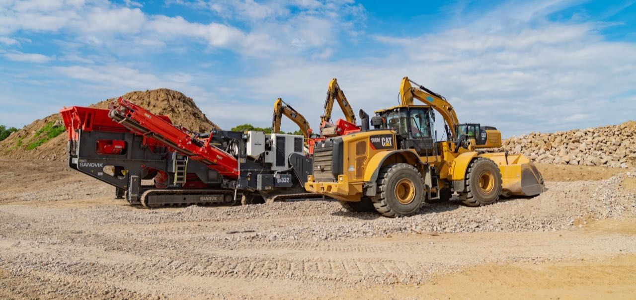 Wheel loader and mobile rock crusher among material stockpiles at Applied Materials Logistics.