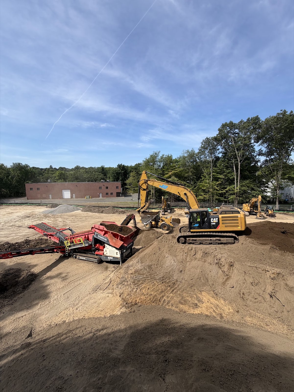 Excavator loading a mobile screening machine at the Timberwood Circle site.