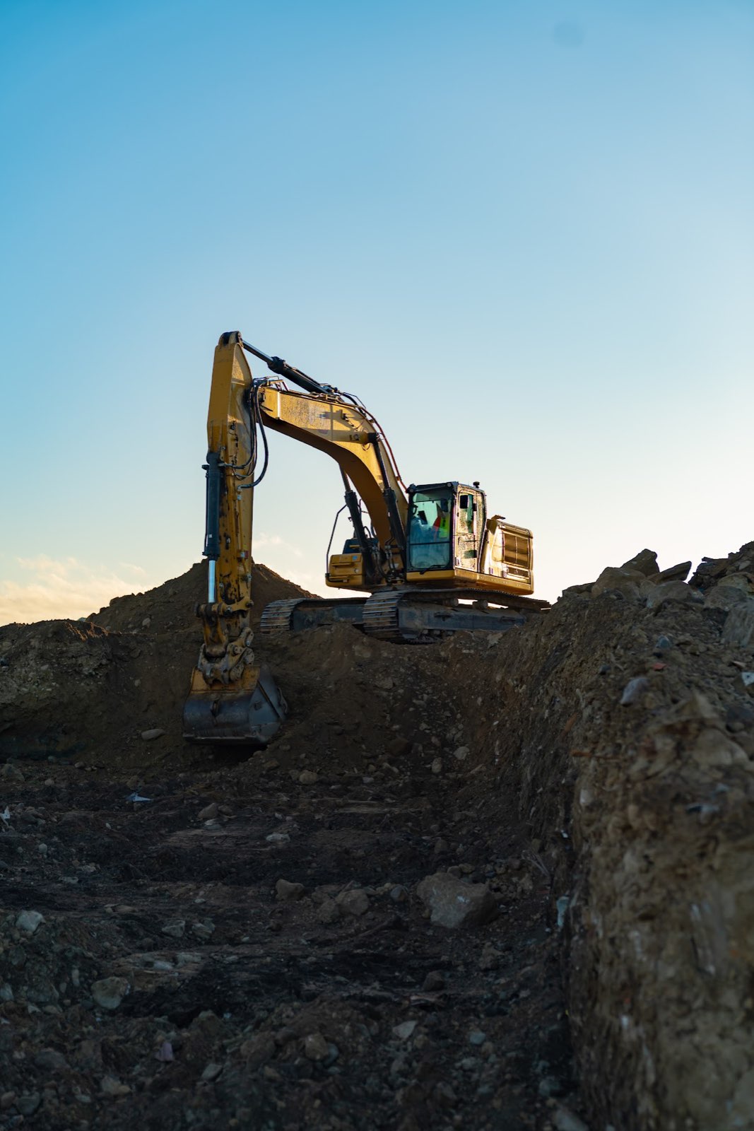 Yellow excavator digging a deep cut at the Waterhouse senior housing site in Danvers.